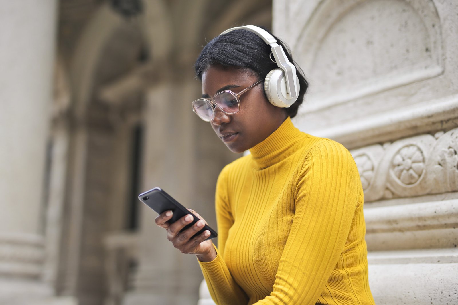 young woman at the entrance of a school listens to music